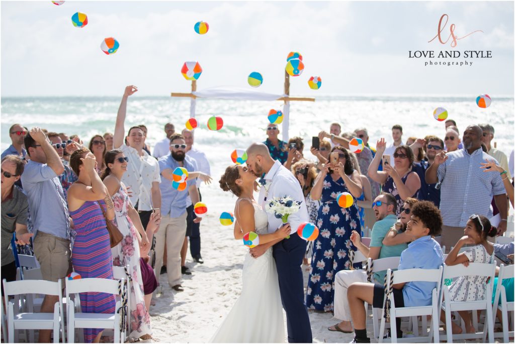 Wedding Photography at The Beach House, Anna Maria Island, couple kissing while guests toss beach balls in the air