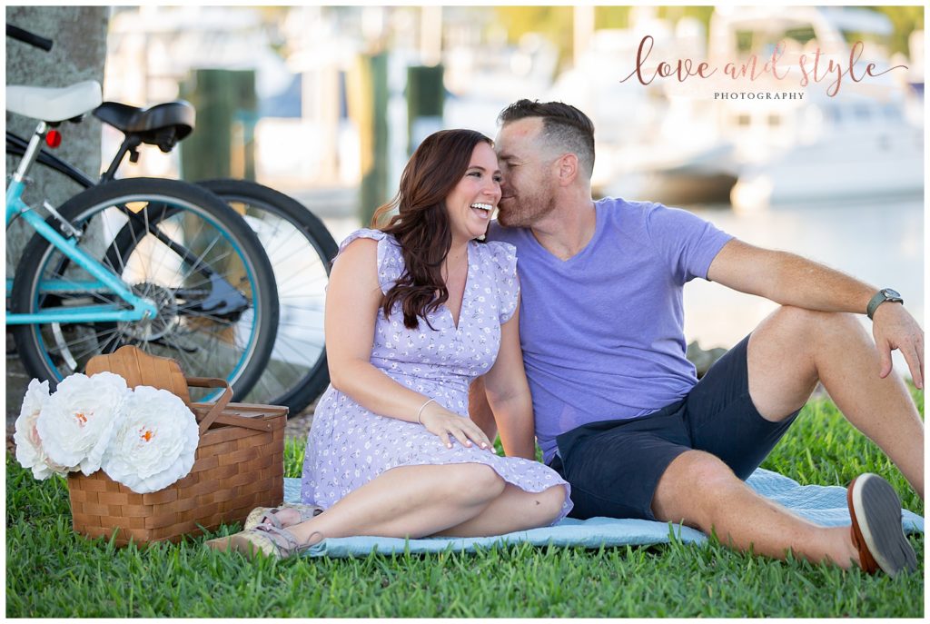 Engagement Photography in Sarasota, Fl at Bayfront Park, couple sitting on a blanket on the grass with bikes leaning on the tree