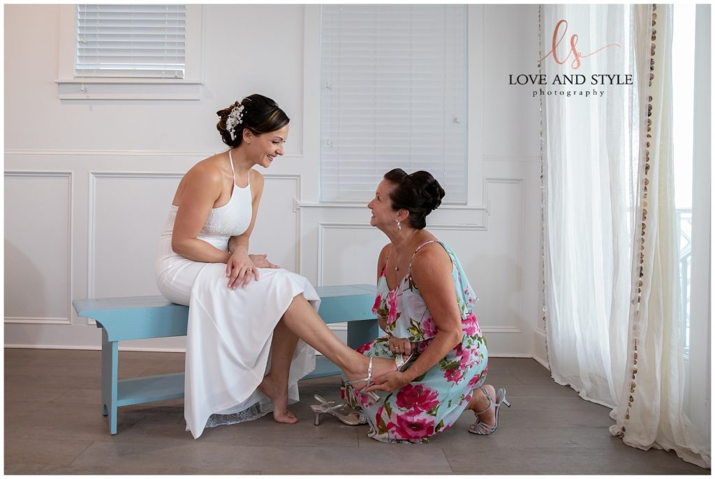 Bride with mom putting her wedding shoes on for her Anna Maria Island Sunset Beach Wedding