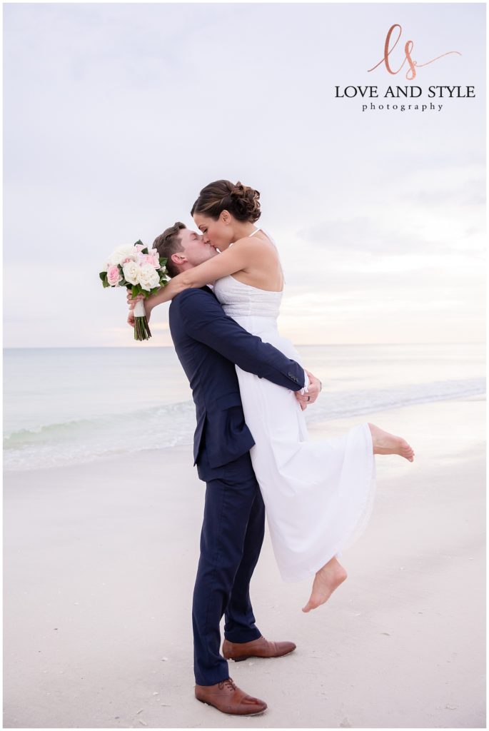 Groom kissing brides forehead on the beach after their Anna Maria Island wedding ceremony 