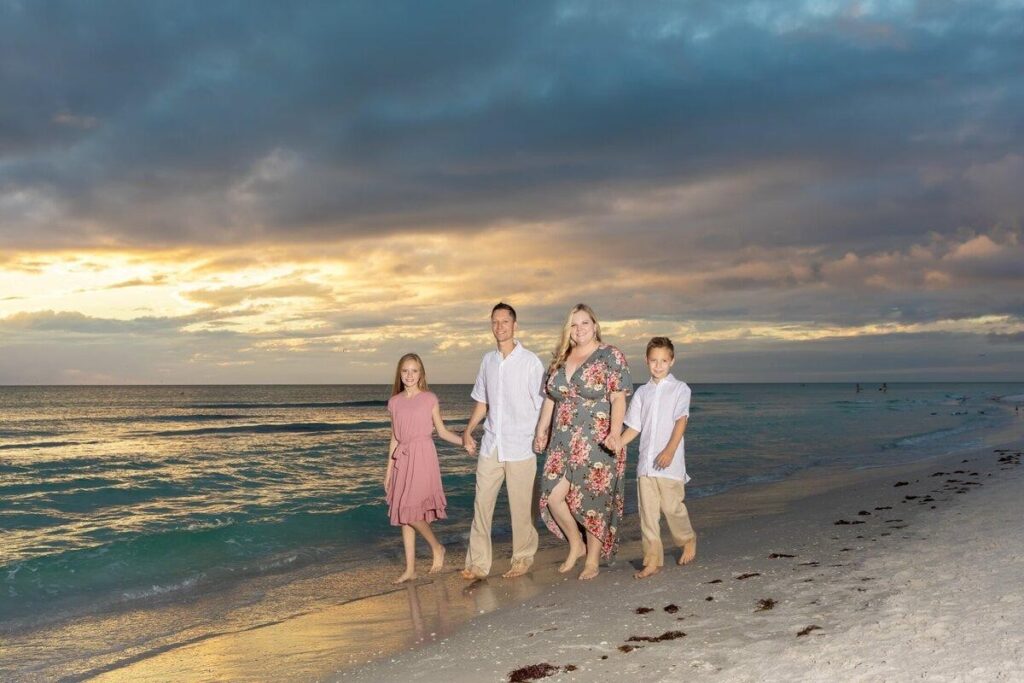 Candid family beach portraits of parents and child walking along the shore at Anna Maria Island