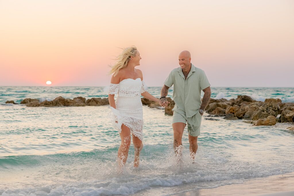 Engaged couple holding hands running through the water on Longboat Key