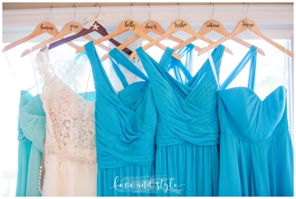 turquoise-bridesmaids-dresses-on-hangers with names on them hanging from doorway