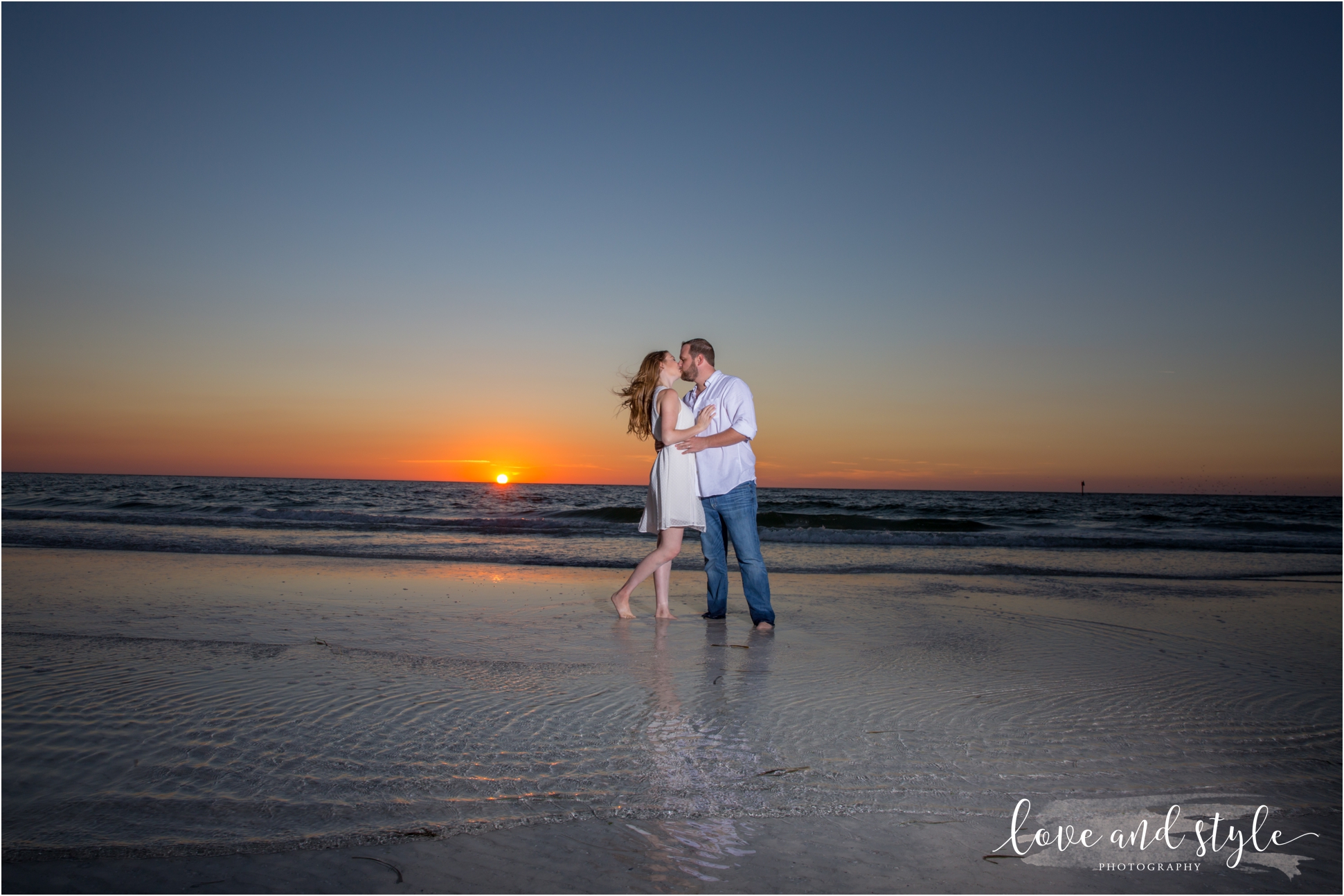 husband and wife kissing in front of the sunset on siesta key beach