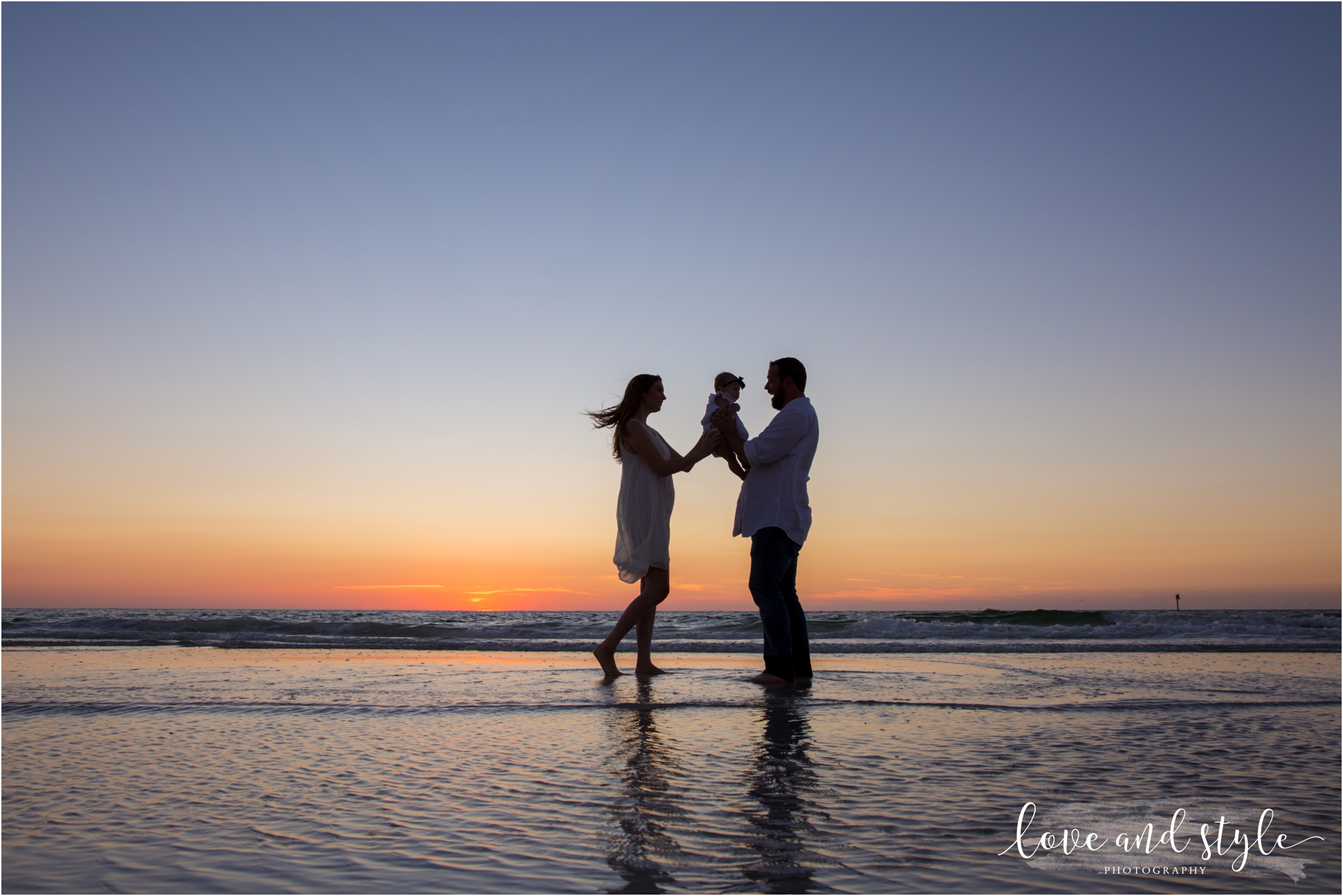 silhouette family of three wearing white on Siesta Key beach at sunset