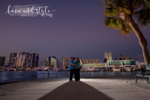 Sarasota Engagement Photographer of couple backlit with downtown Sarasota behind them