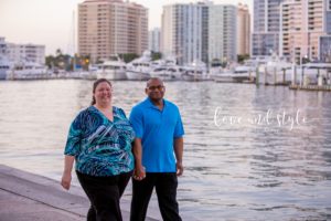 Sarasota Engagement Photographer of couple holding hands and walking with downtown Sarasota behind them