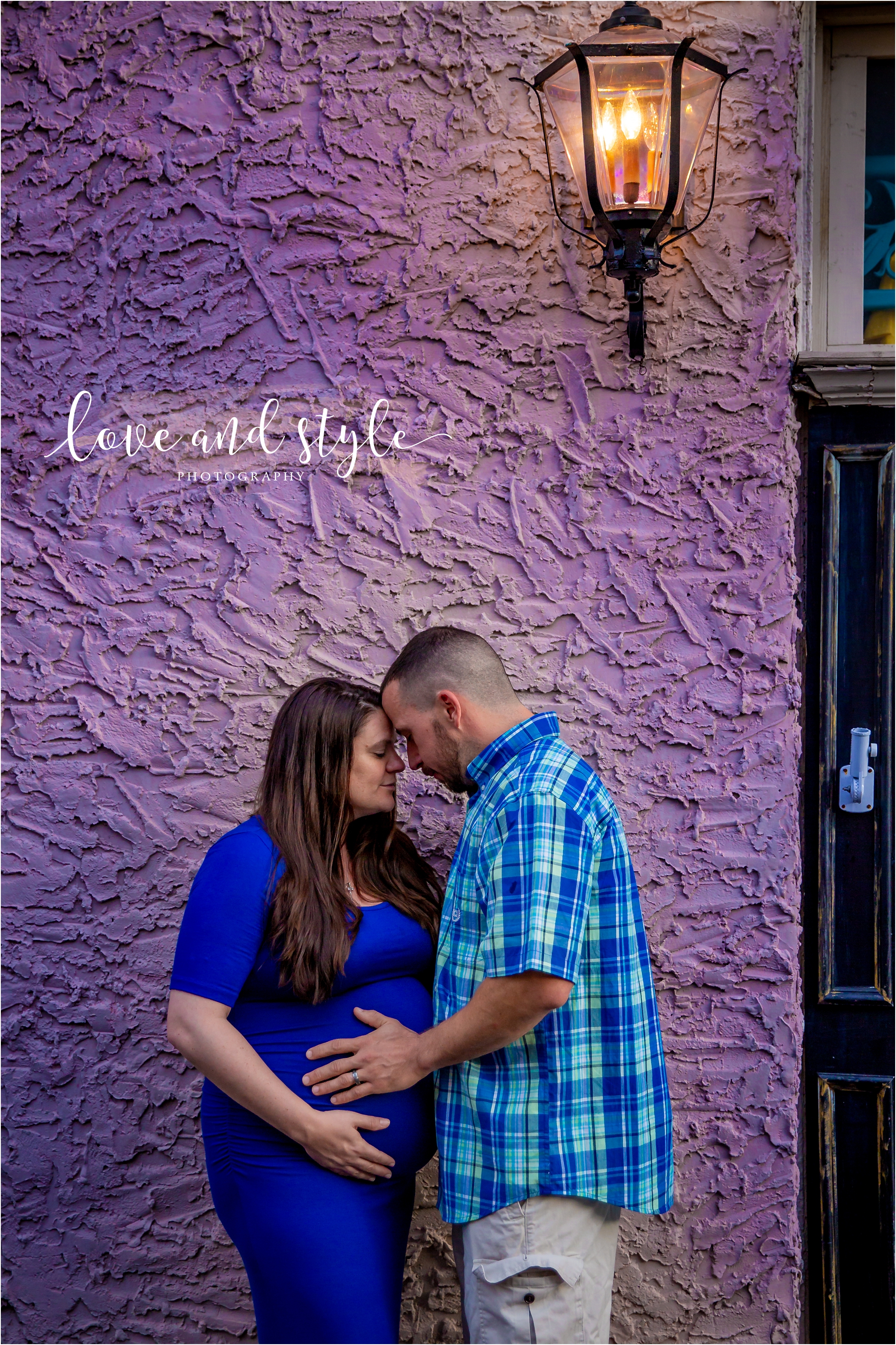Downtown Bradenton maternity Photography of couple wearing blue embracing in front of a pink stucco wall