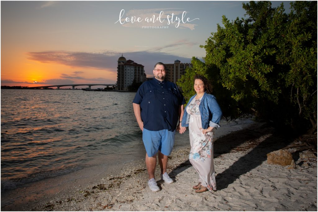 Engagement Photographer Sarasota with couple holding hands and the sunset is behind them