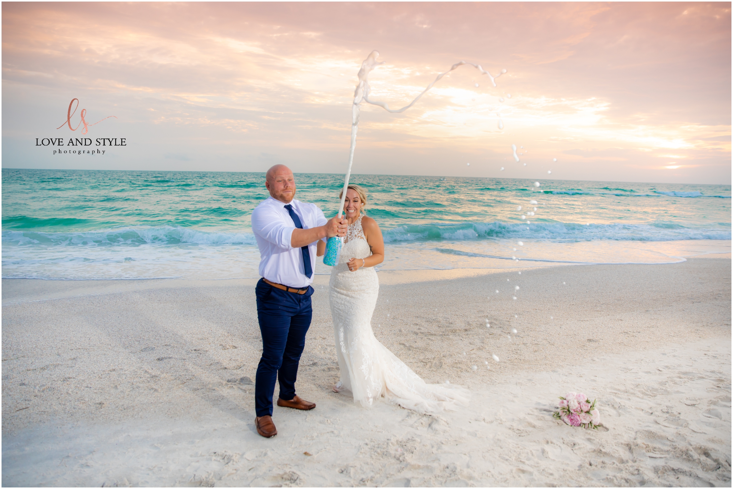 Bride and Groom popping champagne on the beach at sunset