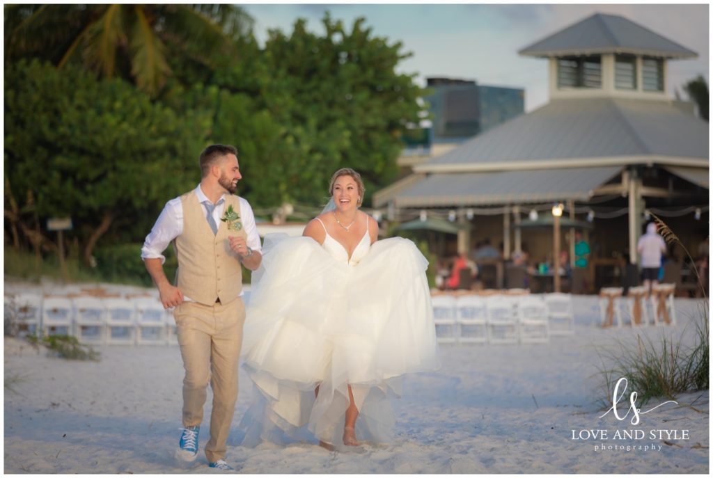 A bride and groom running on the beach after their Wedding at The Sandbar, Anna Maria Island