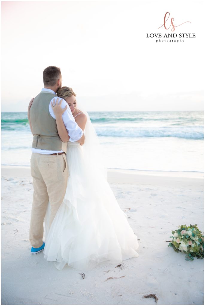 A bride and groom embracing on the beach at sunset on the beach after their Wedding at The Sandbar, Anna Maria Island