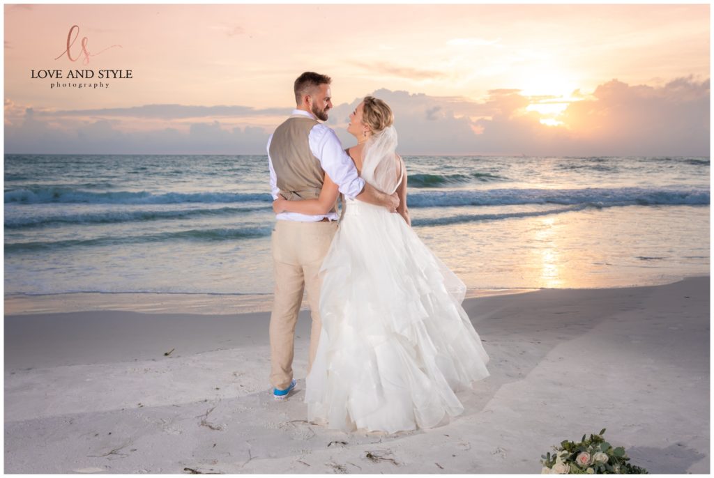 A sunset photo of the bride and groom on the beach at their Wedding at The Sandbar, Anna Maria Island