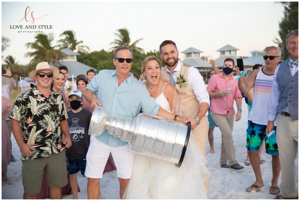 A bride and groom with the coach of the Tampa Bay Lighting with the Stanley Cup at Wedding at The Sandbar, Anna Maria Island