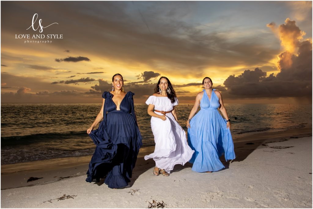 3 sisters in flowing dresses on the beach at sunset