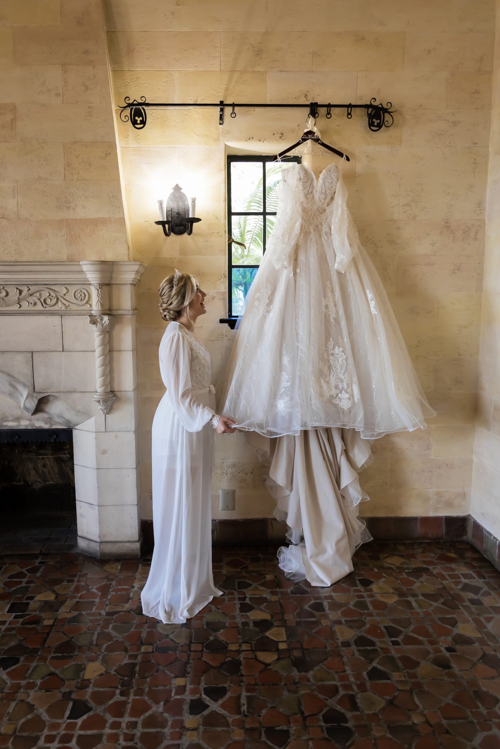 Bride looking at her beautiful dress hanging in the window at the Powel Crosley Estate