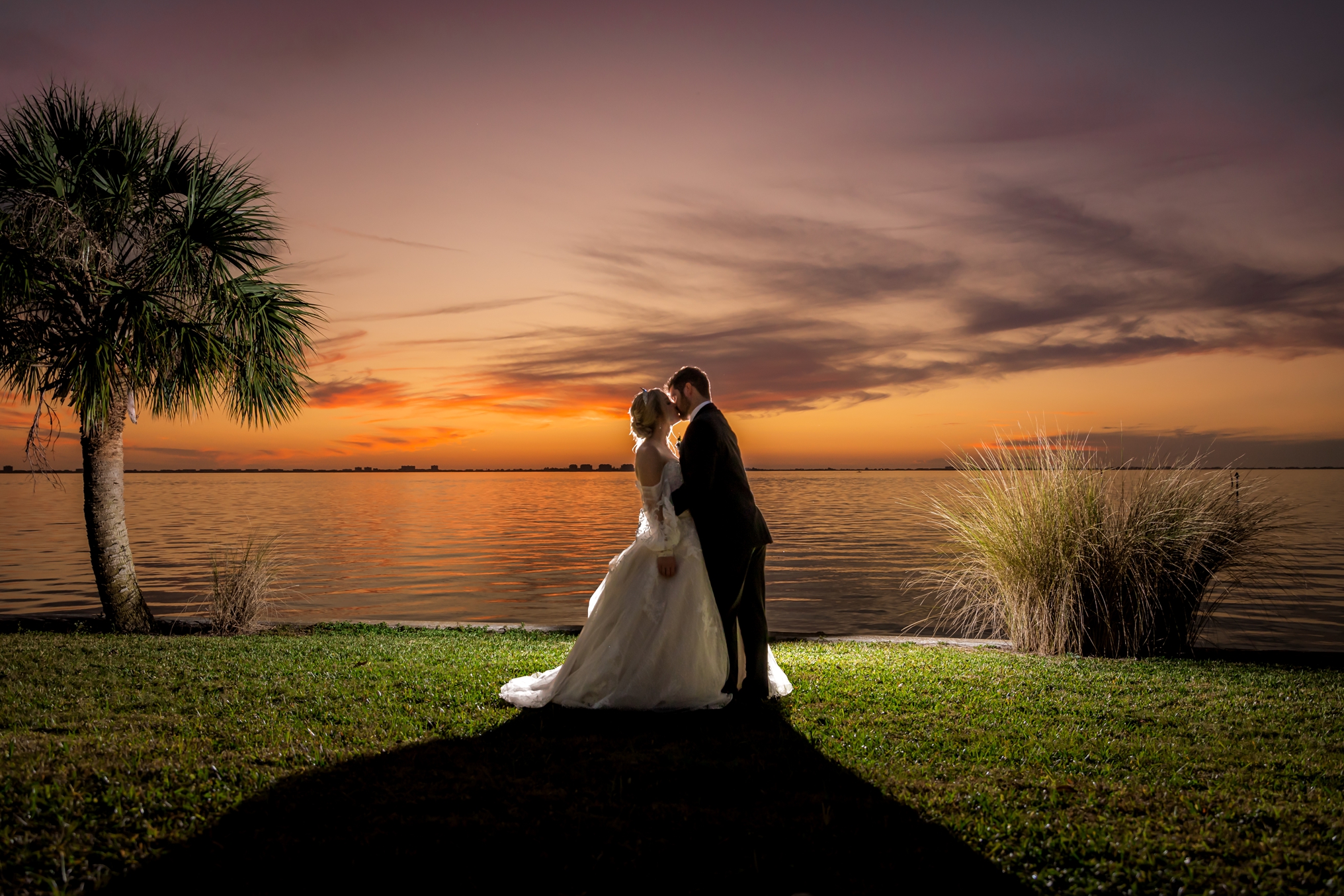 Wide angle backlit photo of married couple Ethan and Morgan at the Powel Crosley Estate facing the Sarasota Bay.