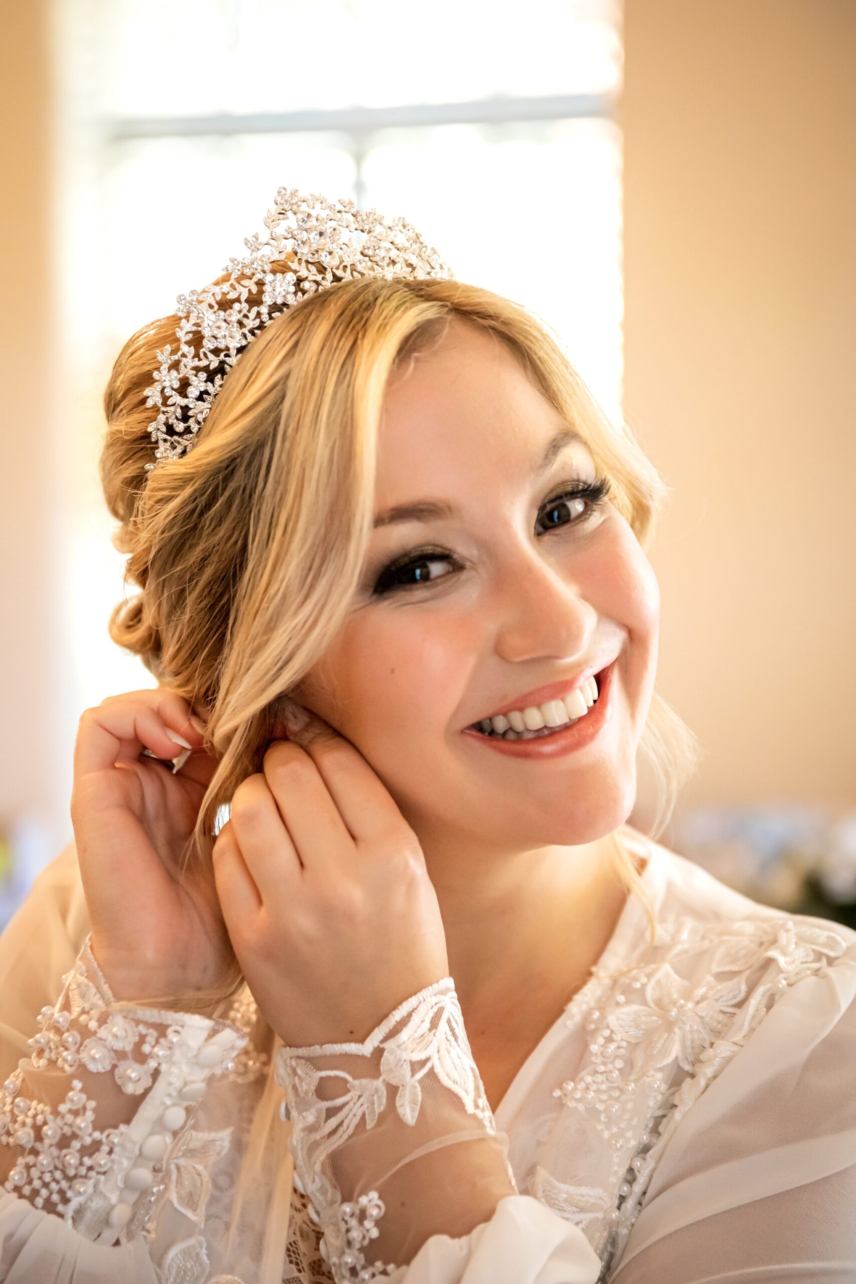 Bride, Morgan, putting on her earrings and smiling at the camera