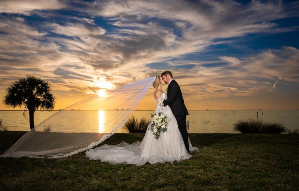 Bride and groom kissing at sunset with flowing veil during a wedding session by Sarasota engagement photographer Love and Style Photography.