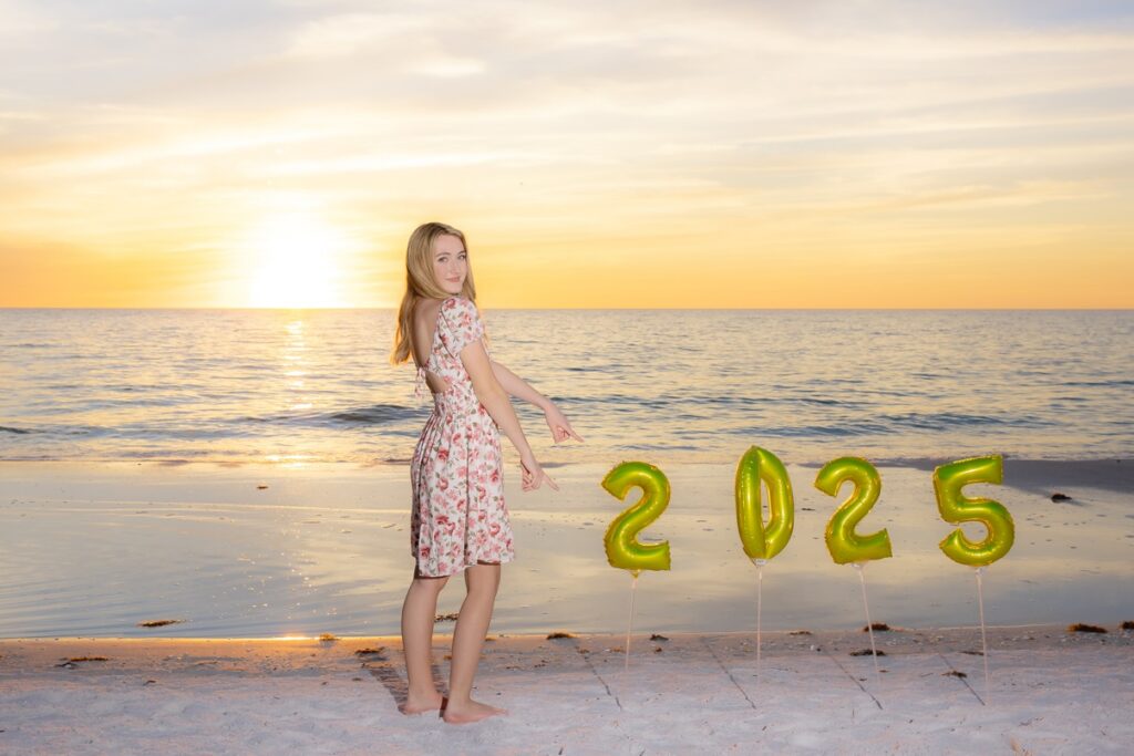 Senior girl at the beach at sunset with 2025 balloons.